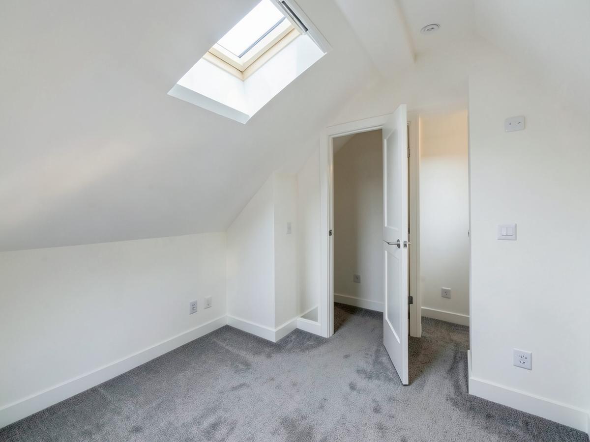 Finished dormer loft conversion bedroom with rooflight and en-suite door
